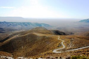 Paysage aride du Karoo en Afrique du Sud, avec des collines rocheuses et un ciel bleu lumineux.