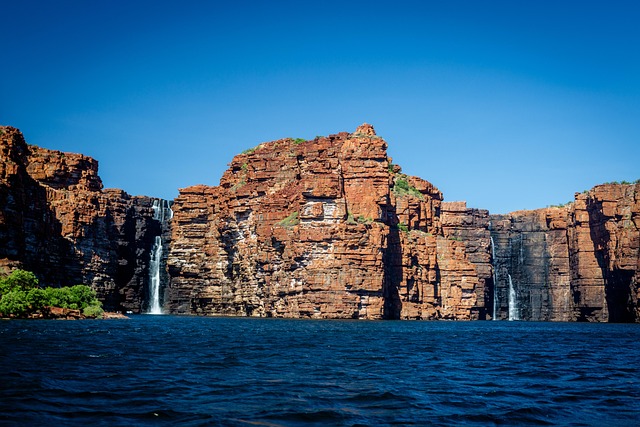 Vue spectaculaire de la région de Kimberley, avec une cascade se jetant dans l’océan et des falaises rocheuses en arrière-plan.