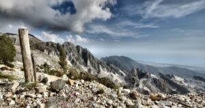 Vue panoramique d’une carrière de marbre blanc à ciel ouvert dans les montagnes de Toscane, près de Carrara, avec les pentes sculptées par l’extraction et un ciel bleu en arrière-plan.