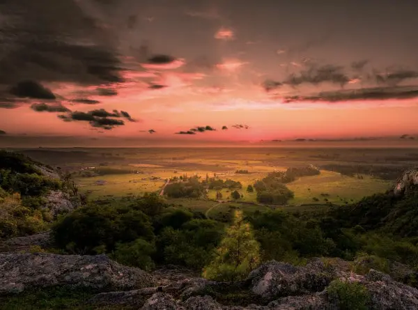 Paysage naturel de la région d’Artigas au coucher du soleil, montrant des collines et plaines baignées de lumière dorée.
