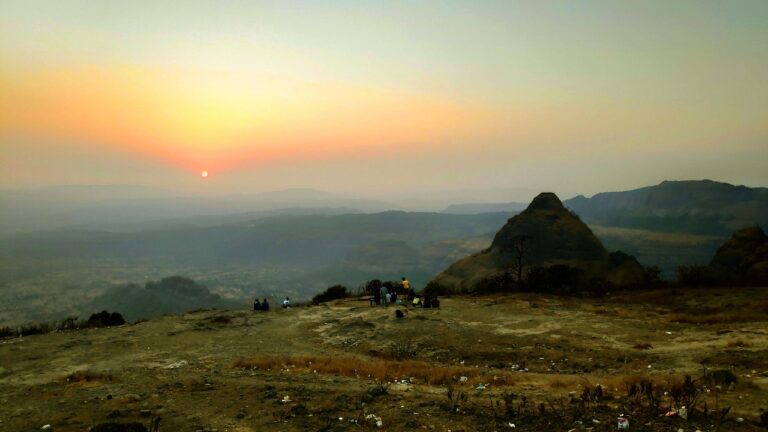 Vue panoramique de Poona avec les collines environnantes au coucher du soleil, ciel aux teintes orangées et violettes, silhouette de la ville à l’avant-plan, Inde.